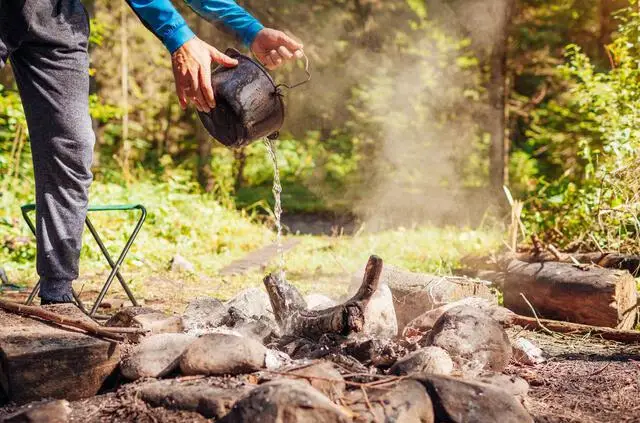 man trowing water to Extinguish Campfire