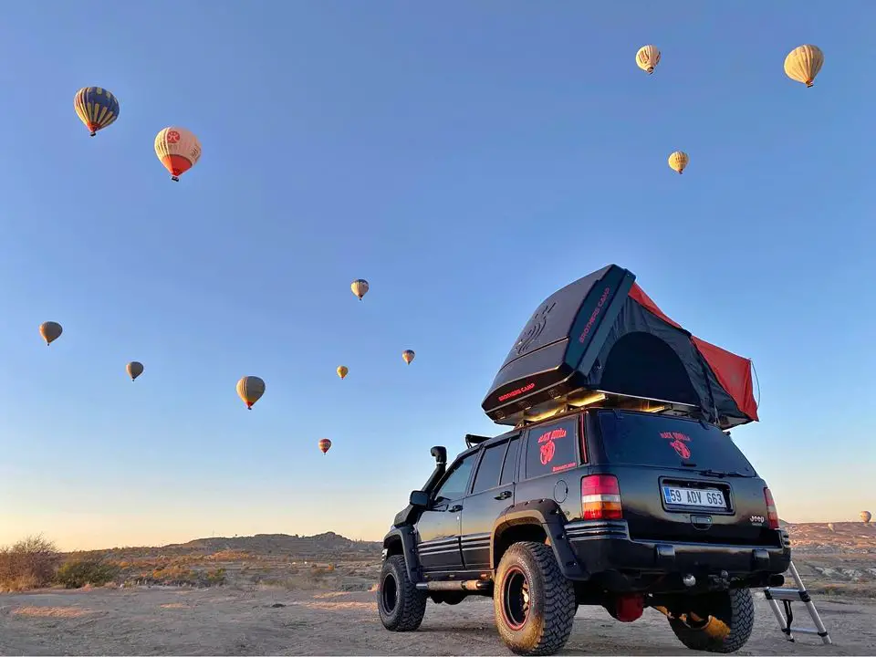 roof tent on a jeep in the desert with hotair balloons