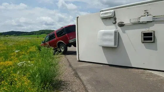 tipped over camper with red car towing