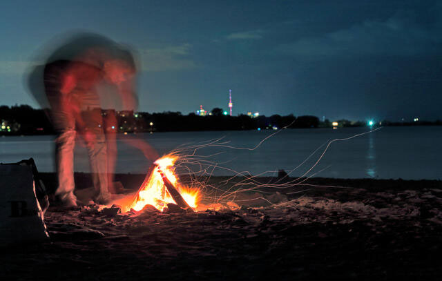 fire camp on a beach at night with a man