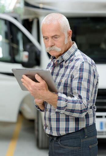man checking tablet with a RV in the background