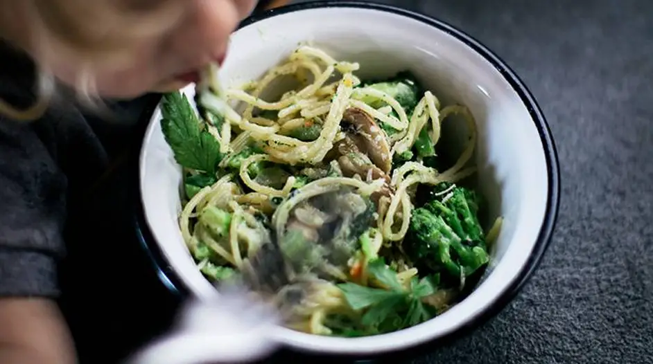 a kid eating a Mushroom and Broccoli Pasta in a white bowl